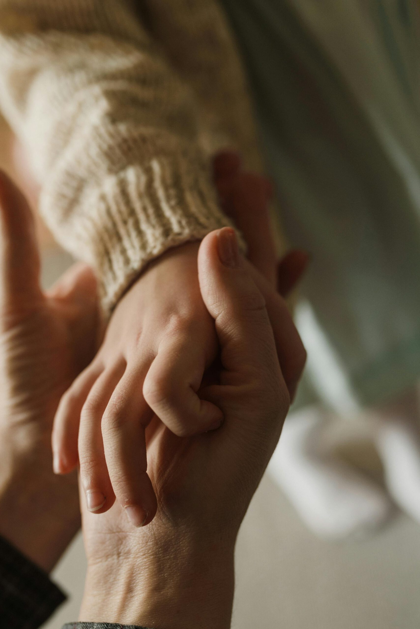 Warm close-up of an adult and child holding hands symbolizing love and care.
